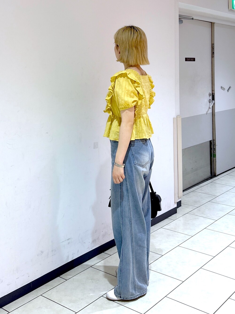 シルバー系のスニーカー、ブルー系のデニムパンツ、イエロー系のシャツ/ブラウスを着用したレディースの夏コーディネートの2枚目の写真