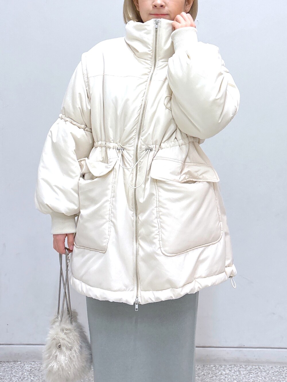 グリーン系のワンピース、ホワイト系のその他アウター、ブラック系のベルトを着用したレディースの冬コーディネートの6枚目の写真