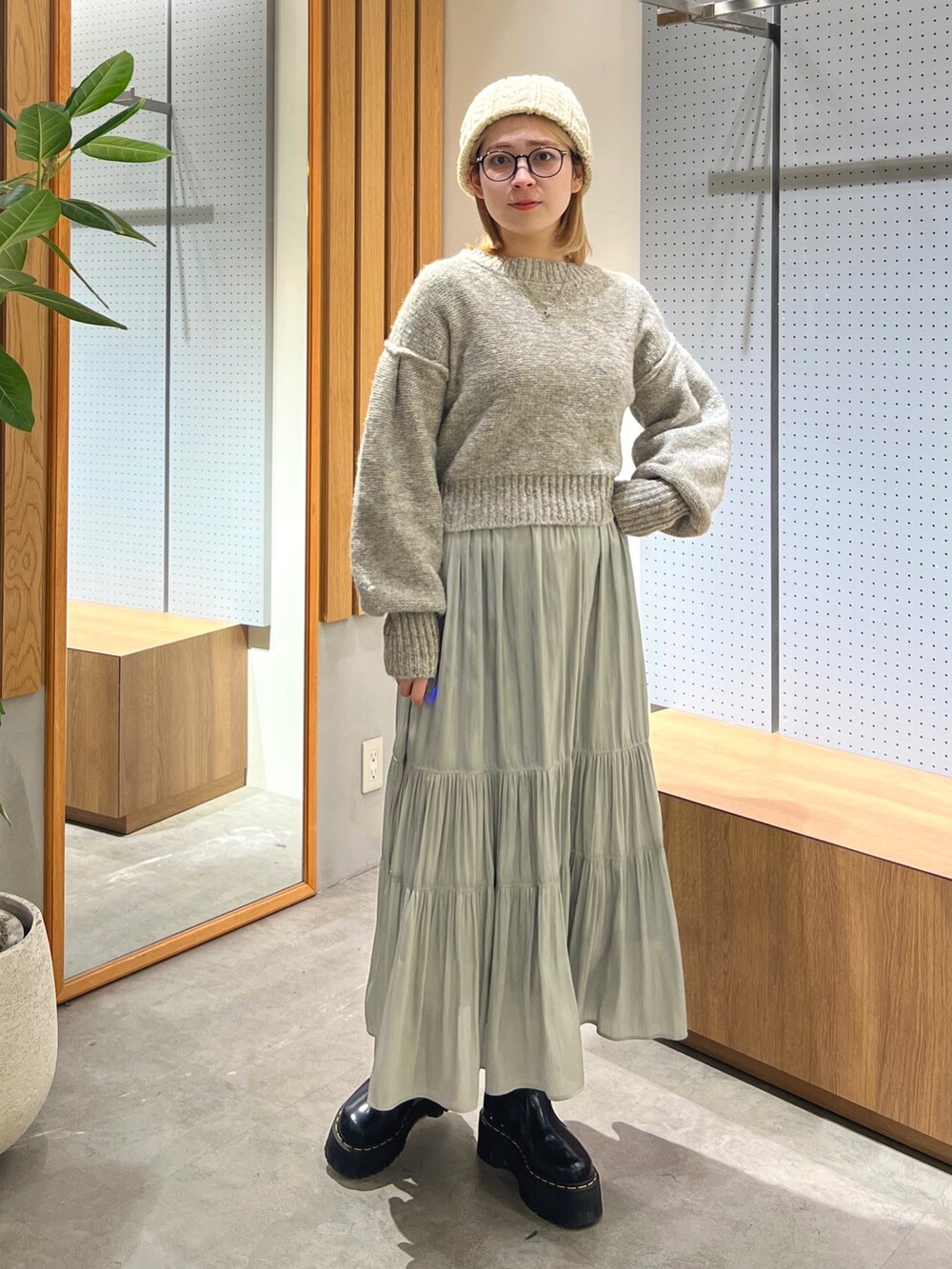 グレー系のニット/セーター、グリーン系のスカート、ホワイト系のニットキャップ/ビーニーを着用したレディースの冬コーディネートの6枚目の写真