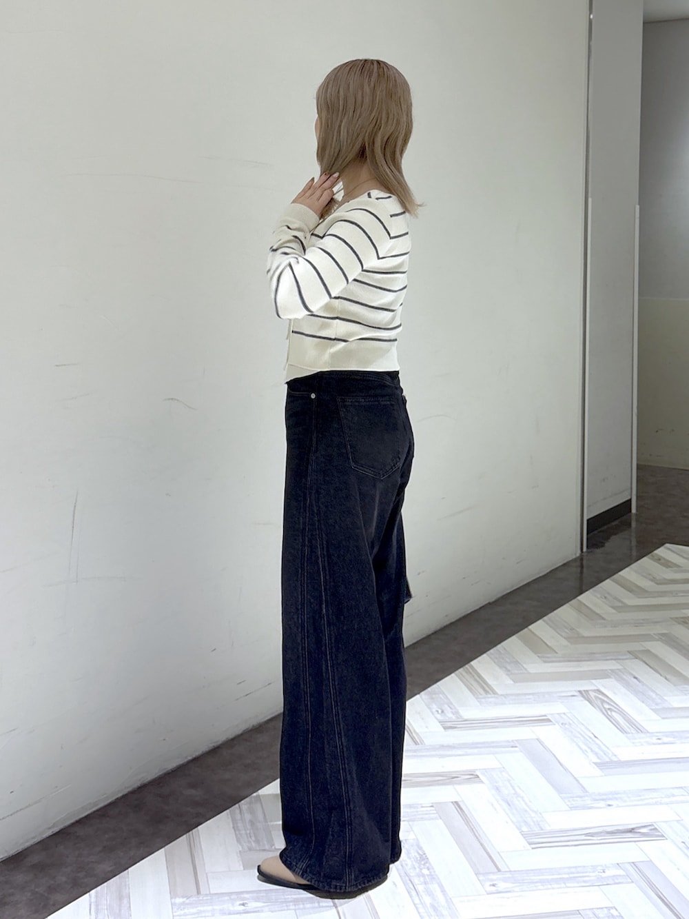 ブラック系のデニムパンツ、ホワイト系のニット/セーター、ブラック系のショルダーバッグを着用したレディースの秋コーディネートの2枚目の写真