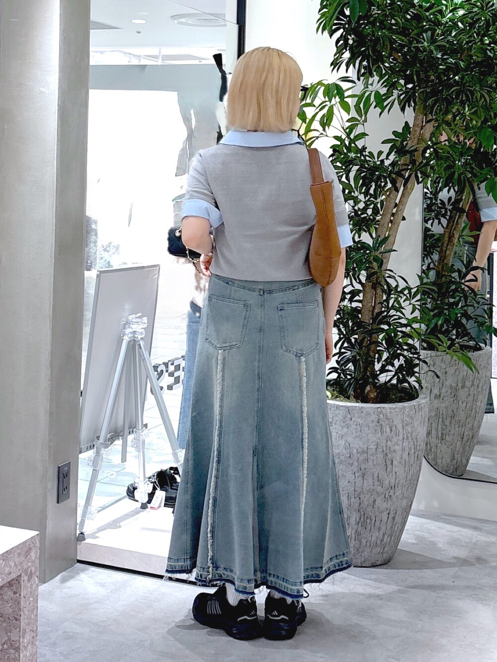 グレー系のニット/セーター、ブルー系のスカート、ブラウン系のハンドバッグを着用したレディースの夏コーディネートの3枚目の写真