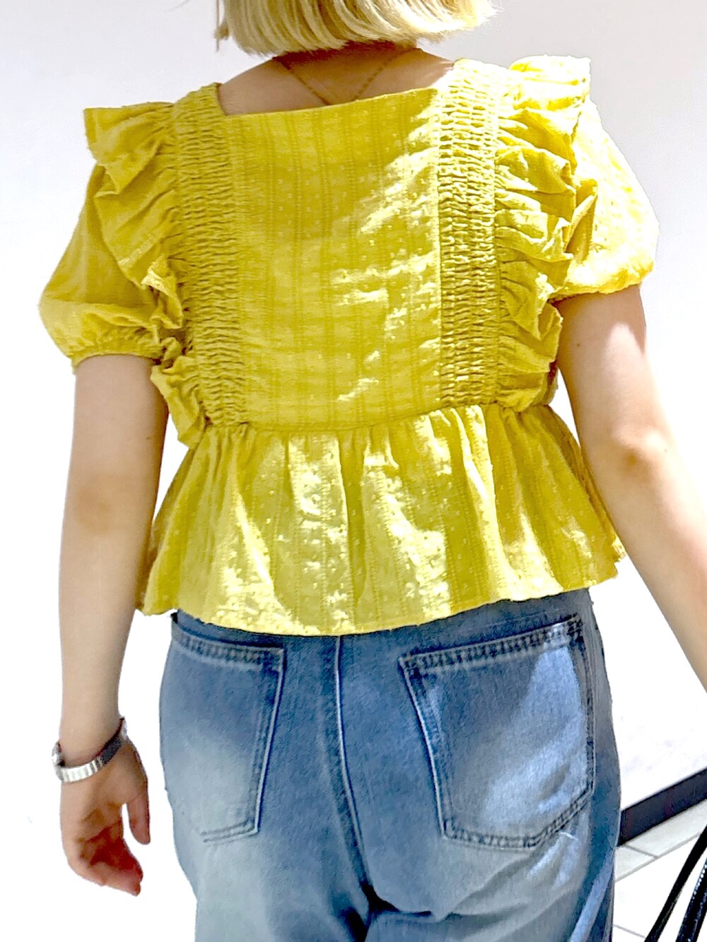 シルバー系のスニーカー、ブルー系のデニムパンツ、イエロー系のシャツ/ブラウスを着用したレディースの夏コーディネートの5枚目の写真