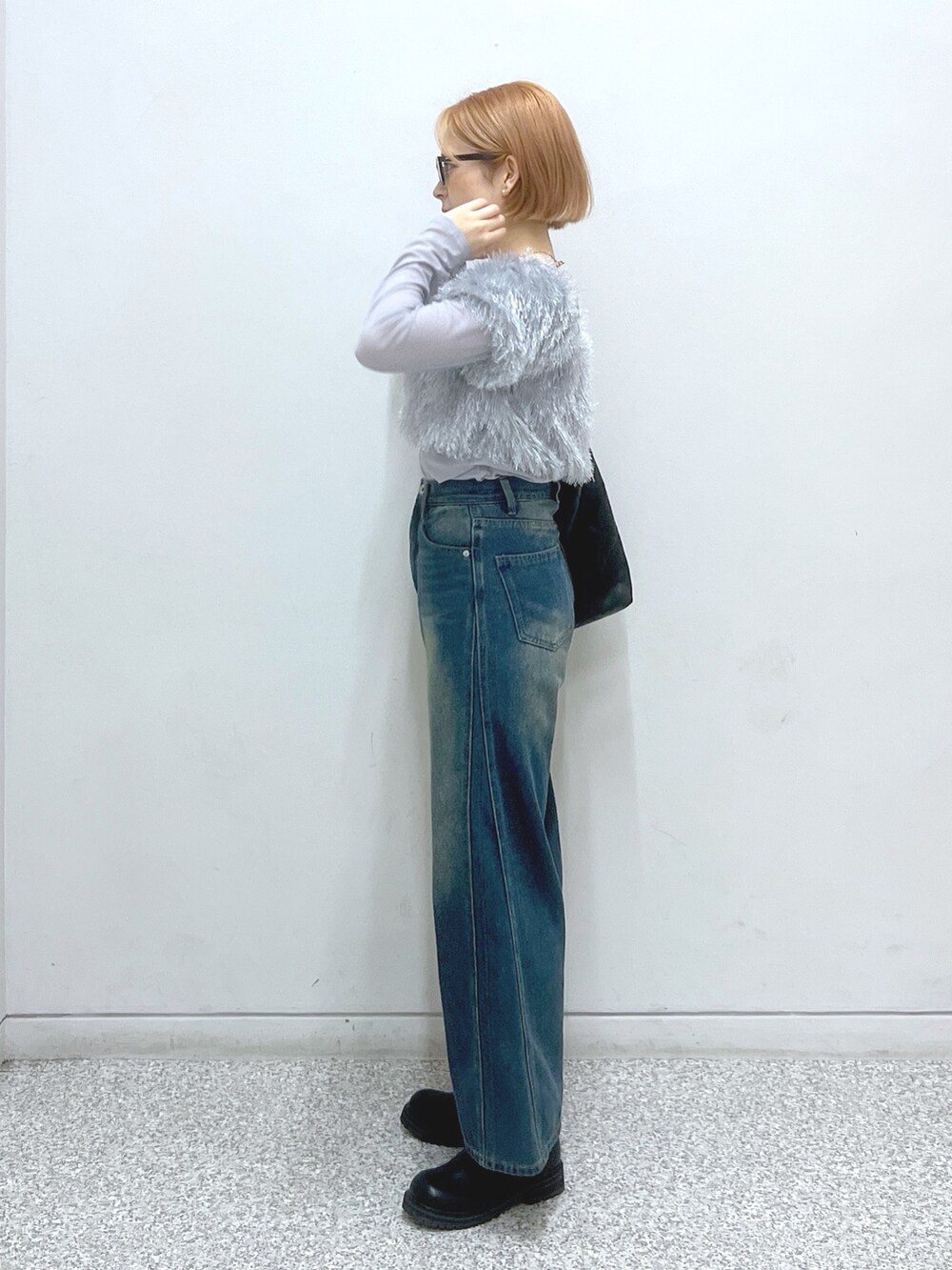 ブルー系のデニムパンツ、ベージュ系のブーツ、ブラック系のトートバッグを着用したレディースの秋コーディネートの2枚目の写真