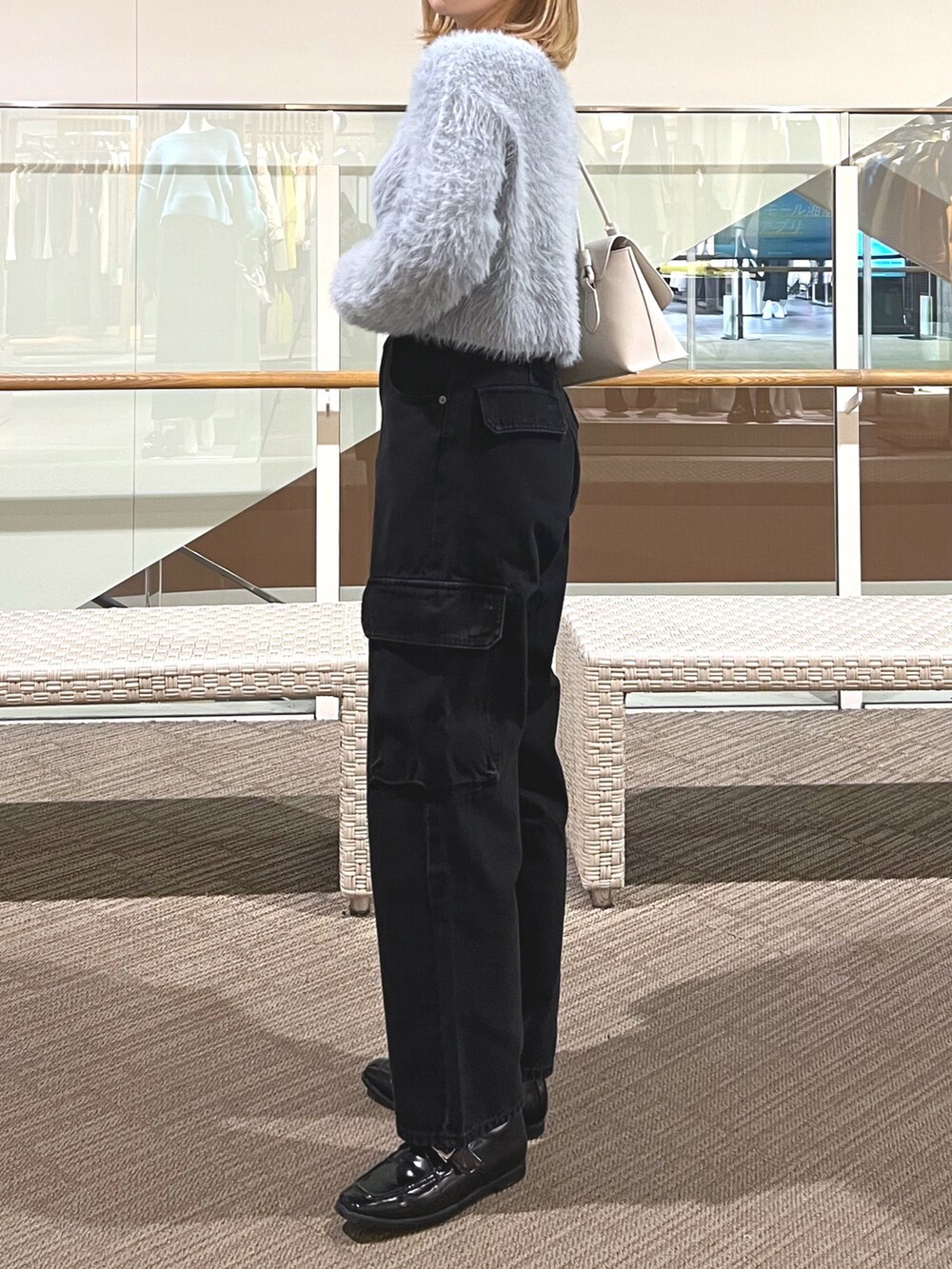 ブラック系のデニムパンツ、ブラック系のローファー、パープル系のショルダーバッグを着用したレディースの冬コーディネートの4枚目の写真