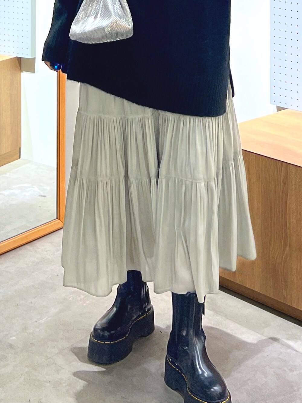 ブラック系のニット/セーター、シルバー系のショルダーバッグ、ホワイト系のスカートを着用したレディースの冬コーディネートの6枚目の写真