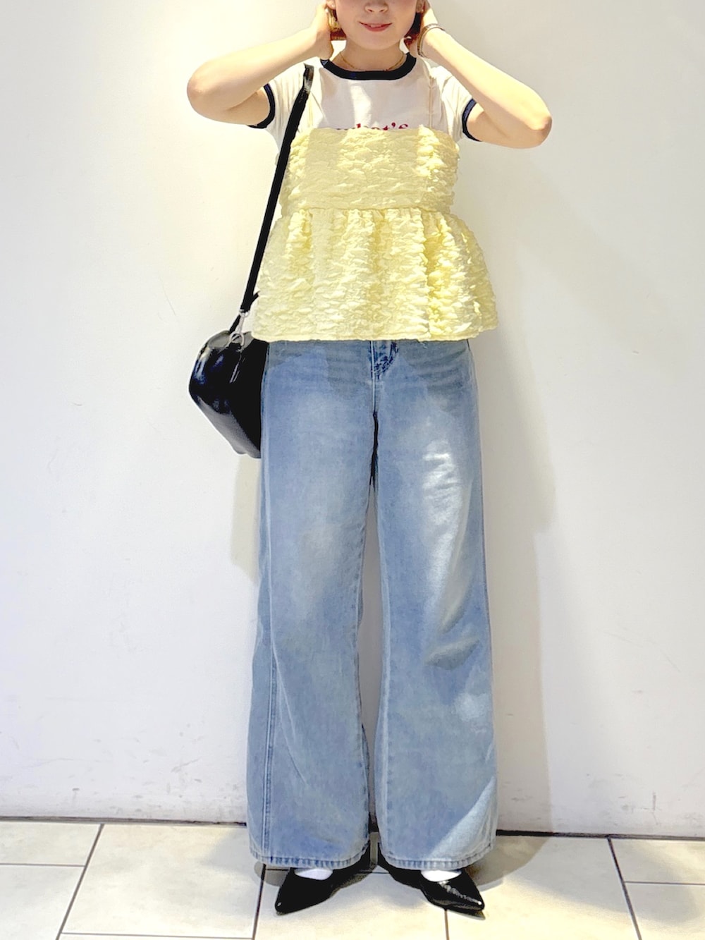 ブラック系のパンプス、ブルー系のデニムパンツ、ブラック系のトートバッグを着用したレディースの夏コーディネートの4枚目の写真