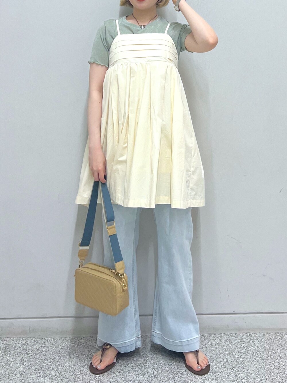 ブルー系のデニムパンツ、ホワイト系のハンドバッグ、グリーン系のTシャツ/カットソーを着用したレディースの夏コーディネートの2枚目の写真