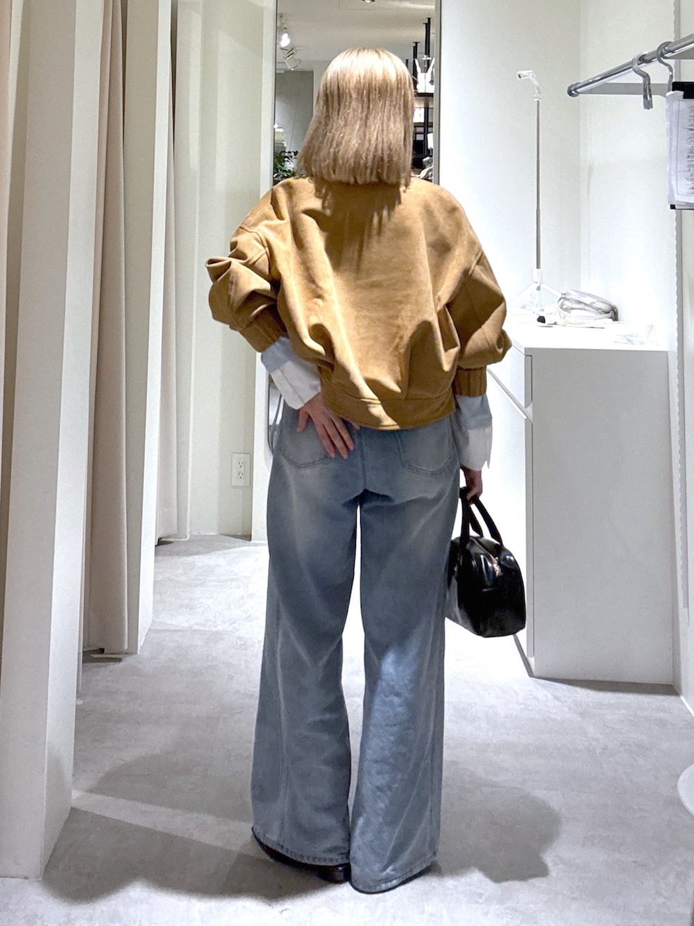 ブルー系のデニムパンツ、ブラック系のハンドバッグ、ブルー系のTシャツ/カットソーを着用したレディースの春コーディネートの3枚目の写真