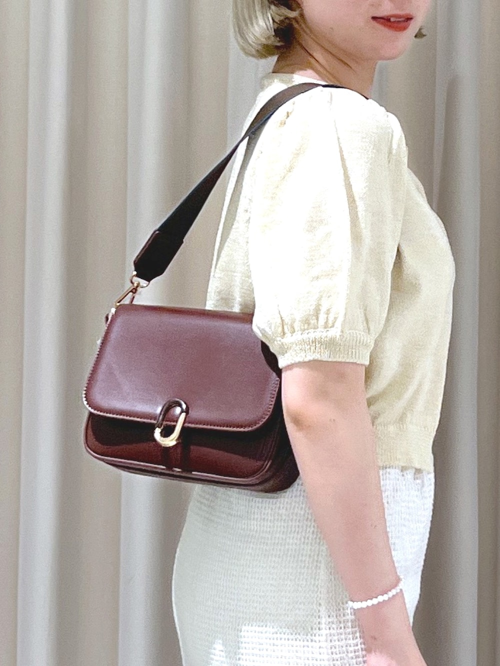 ベージュ系のスリッポン、ベージュ系のショルダーバッグ、ホワイト系のスカートを着用したレディースの夏コーディネートの8枚目の写真