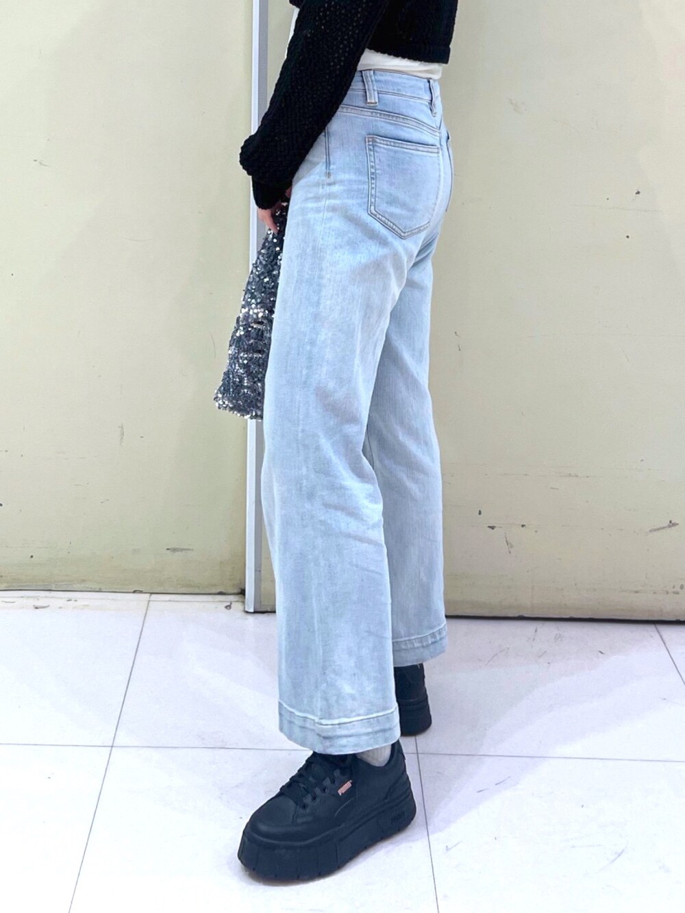 ブラック系のニット/セーター、ブルー系のデニムパンツ、シルバー系のハンドバッグを着用したレディースの春コーディネートの6枚目の写真