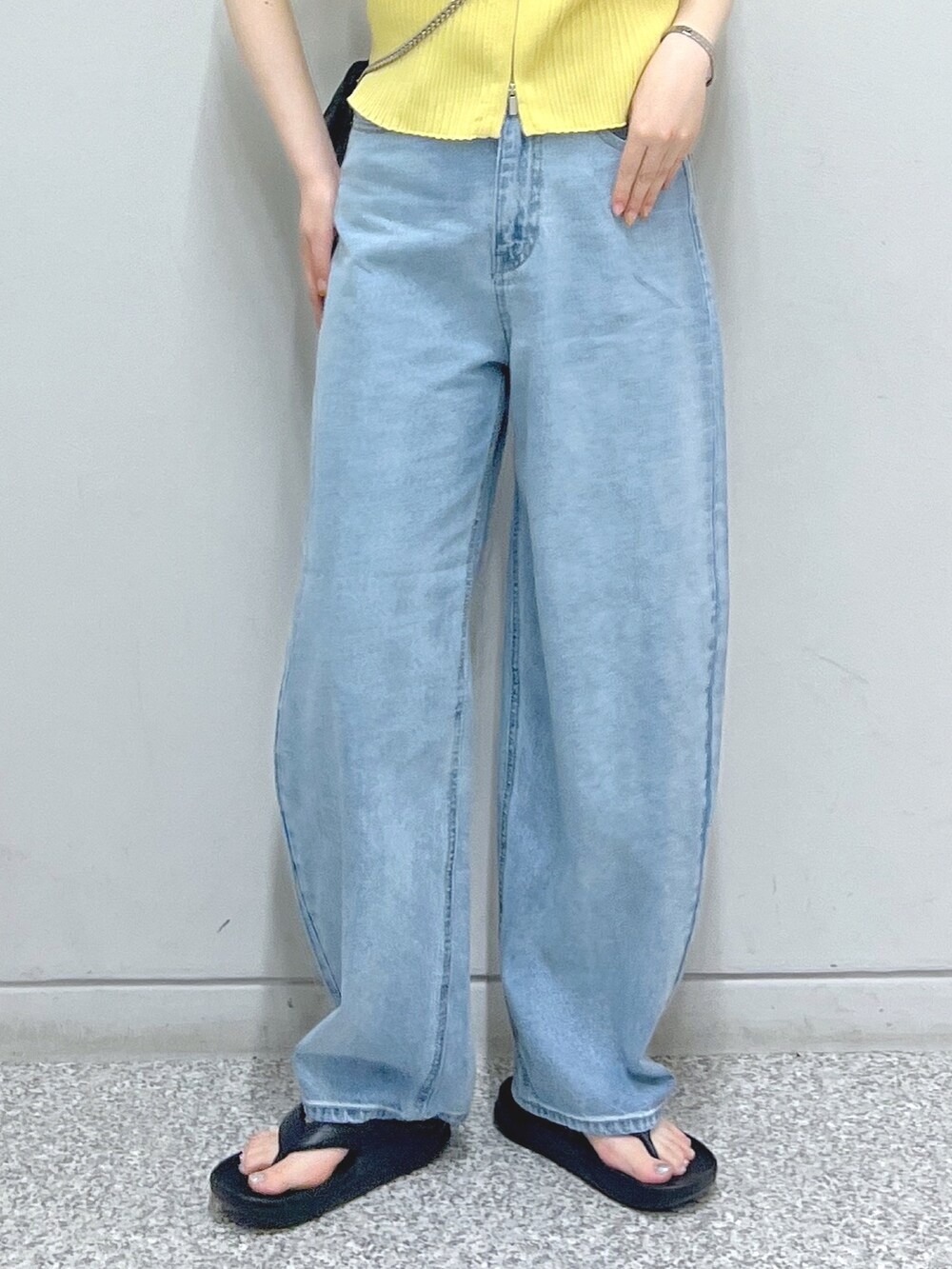 ブルー系のデニムパンツ、ブラック系のショルダーバッグ、イエロー系のニット/セーターを着用したレディースの夏コーディネートの5枚目の写真
