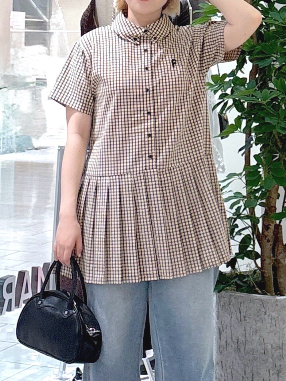 ベージュ系のワンピース、ブルー系のデニムパンツ、ブラック系のトートバッグを着用したレディースの夏コーディネートの4枚目の写真