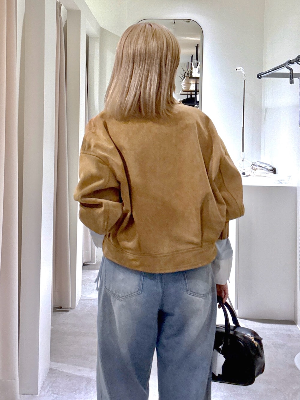 ブルー系のデニムパンツ、ブラック系のハンドバッグ、ブルー系のTシャツ/カットソーを着用したレディースの春コーディネートの5枚目の写真