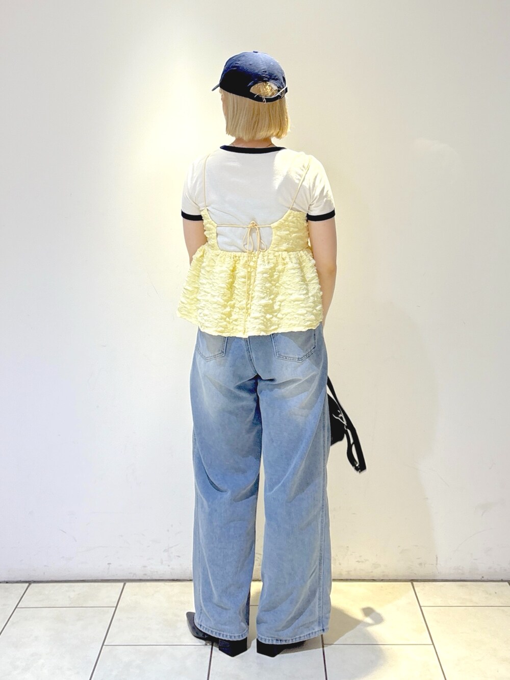 ブラック系のパンプス、ブルー系のデニムパンツ、ブラック系のトートバッグを着用したレディースの夏コーディネートの3枚目の写真