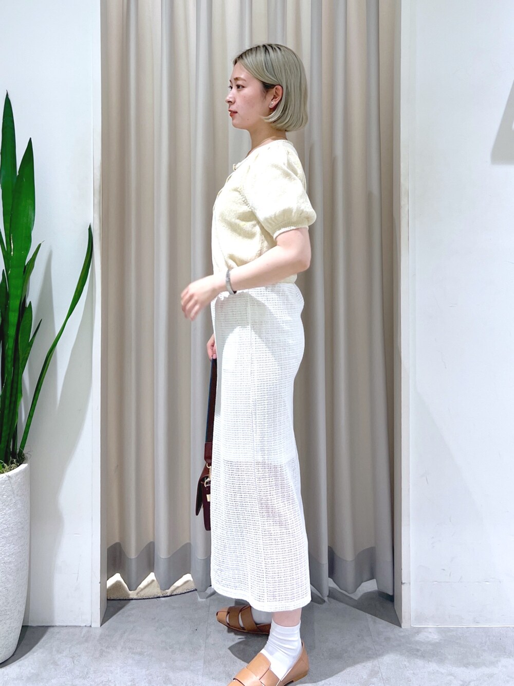 ベージュ系のスリッポン、ベージュ系のショルダーバッグ、ホワイト系のスカートを着用したレディースの夏コーディネートの2枚目の写真