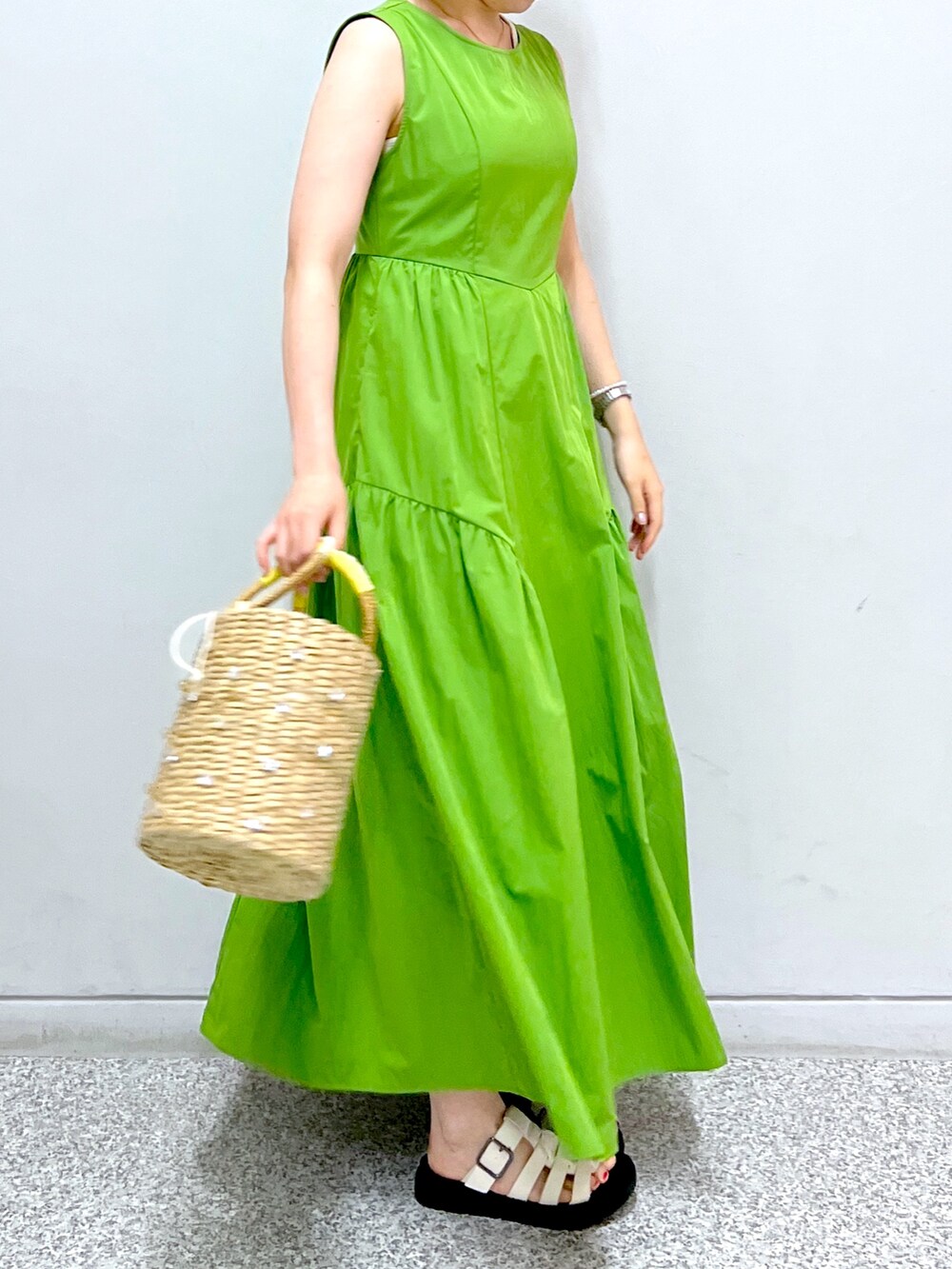 グリーン系のワンピース、イエロー系のかごバッグを着用したレディースの夏コーディネートの5枚目の写真