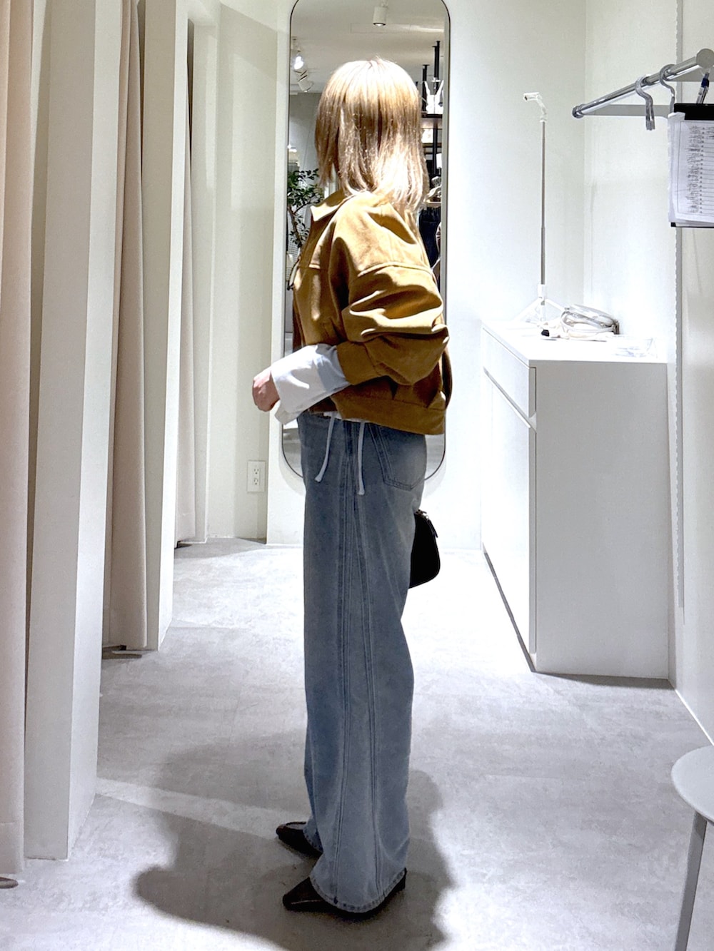 ブルー系のデニムパンツ、ブラック系のハンドバッグ、ブルー系のTシャツ/カットソーを着用したレディースの春コーディネートの2枚目の写真