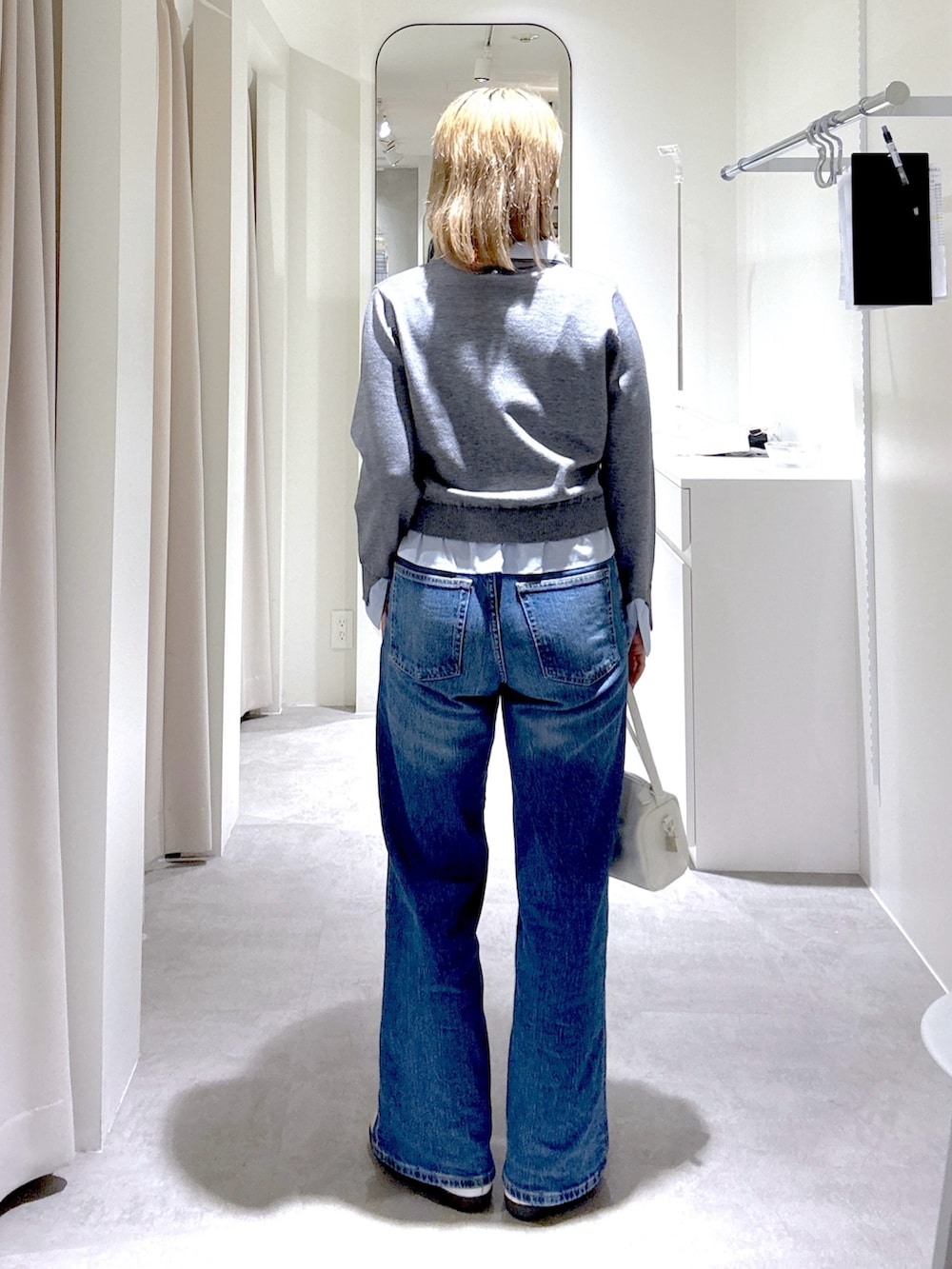 ホワイト系のハンドバッグ、ブルー系のテーラードジャケット、グレー系のニット/セーターを着用したレディースの春コーディネートの8枚目の写真