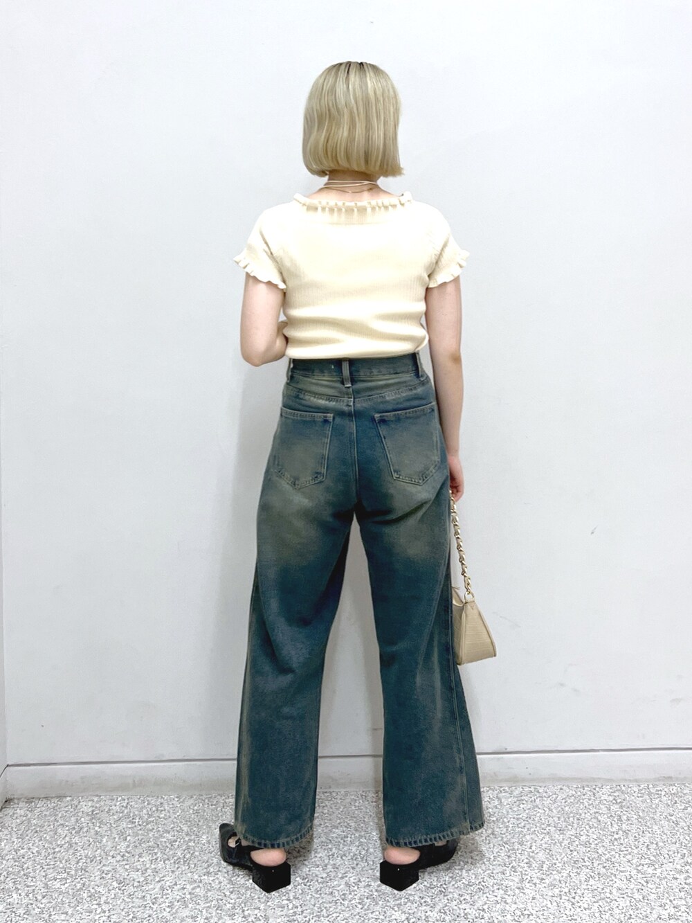 ブルー系のデニムパンツ、ブラック系のパンプス、ベージュ系のトートバッグを着用したレディースの夏コーディネートの3枚目の写真