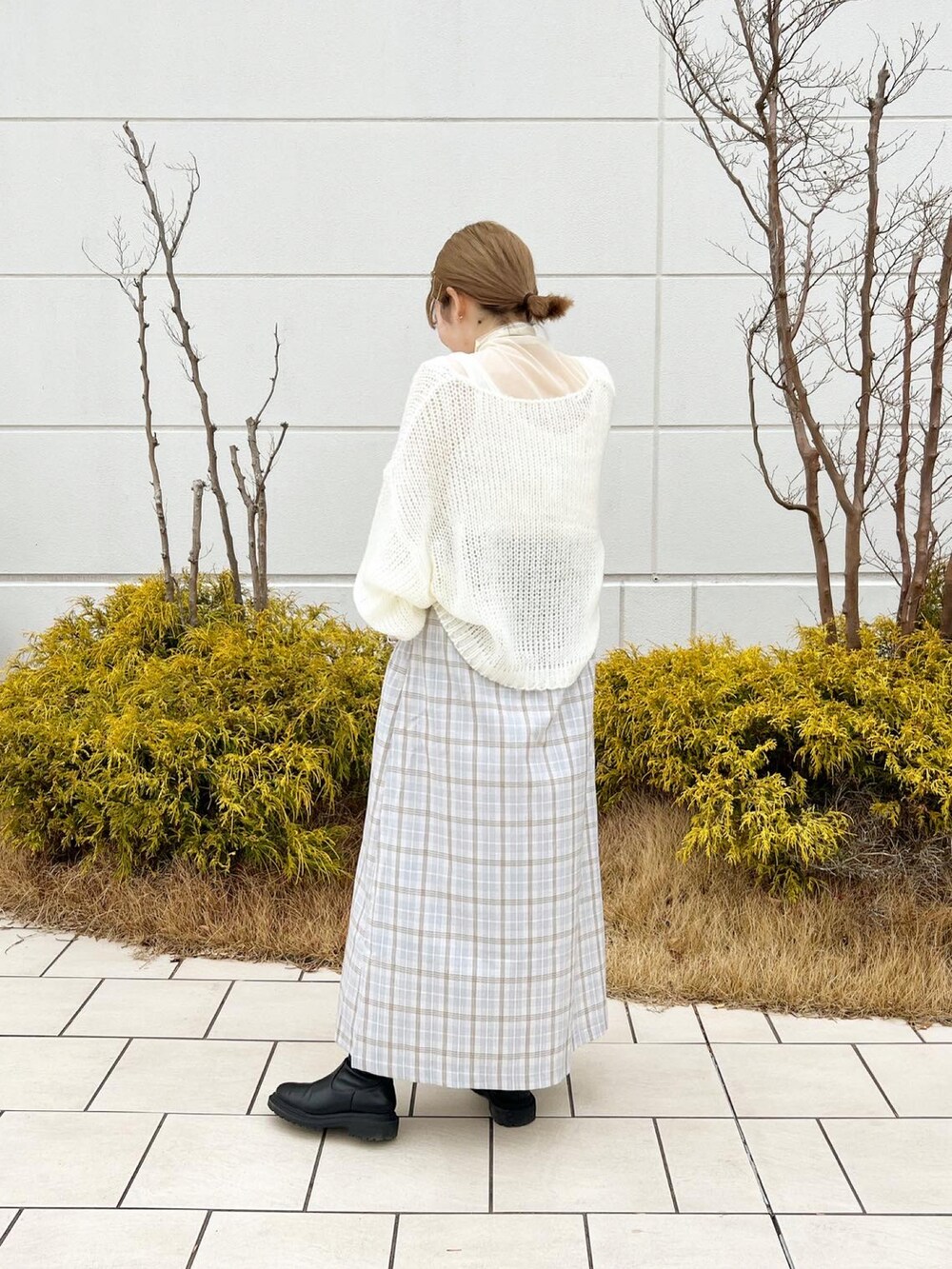 ホワイト系のニット/セーター、パープル系のスカート、ホワイト系のTシャツ/カットソーを着用したレディースの冬コーディネートの4枚目の写真