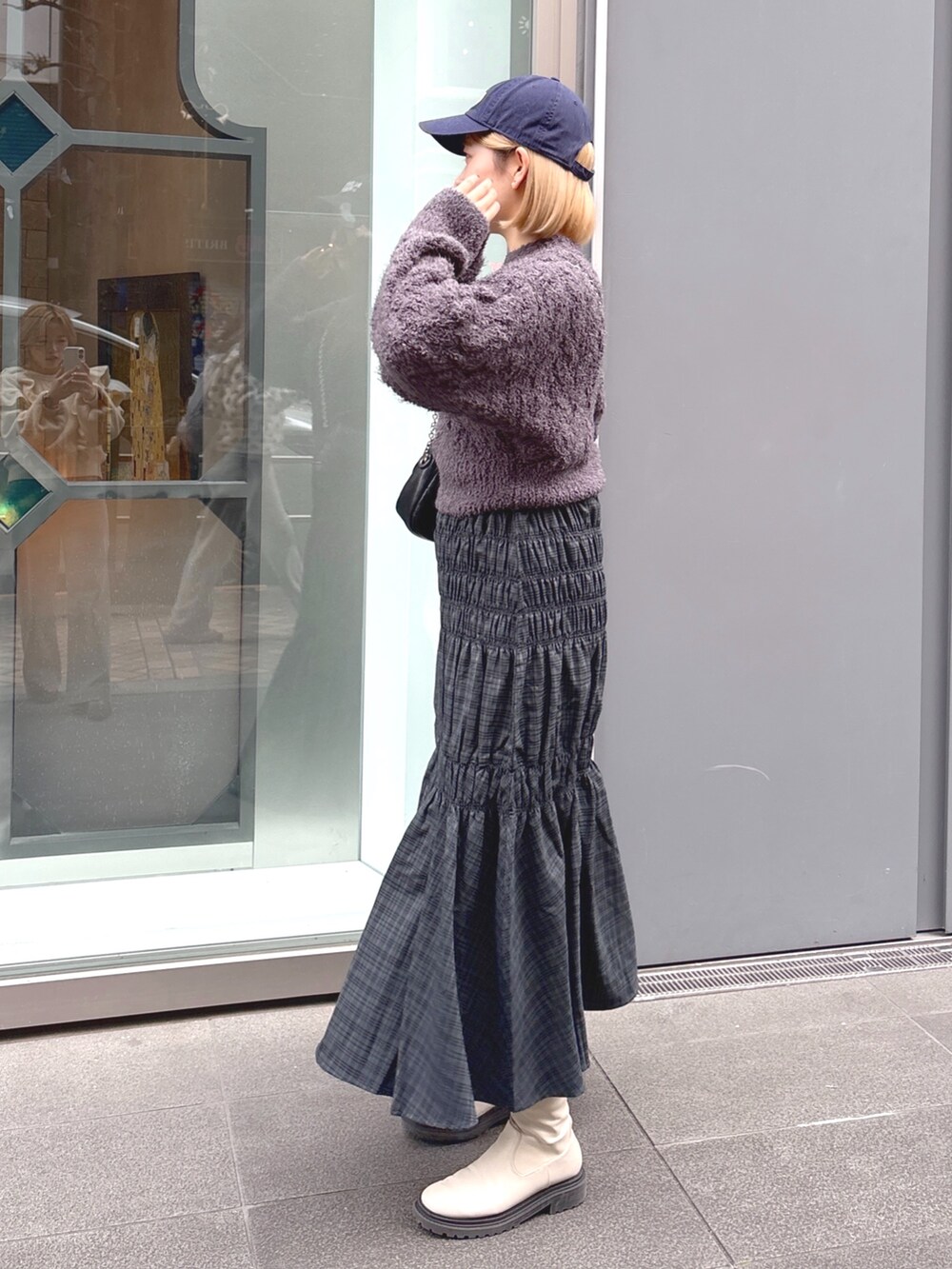グレー系のスカート、グレー系のニット/セーター、ブラック系のショルダーバッグを着用したレディースの冬コーディネートの3枚目の写真