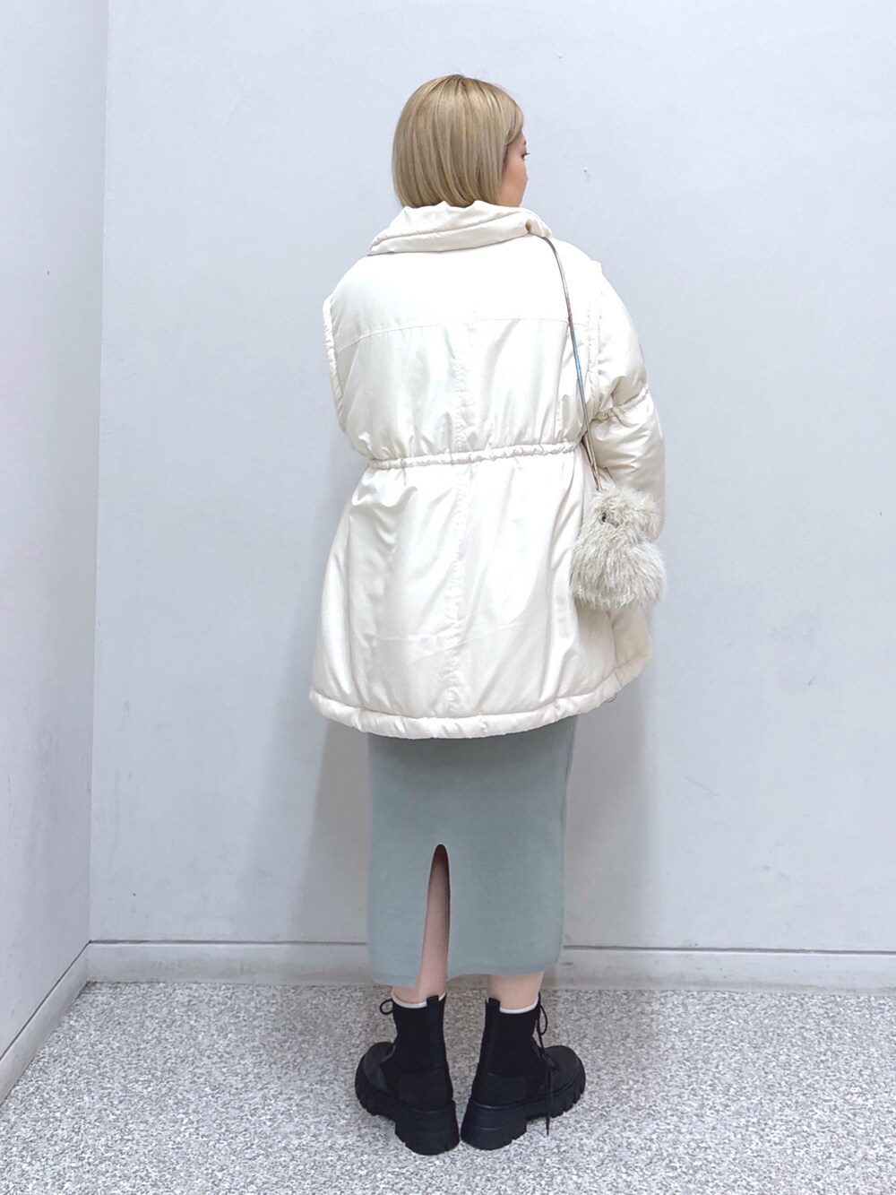 グリーン系のワンピース、ホワイト系のその他アウター、ブラック系のベルトを着用したレディースの冬コーディネートの2枚目の写真