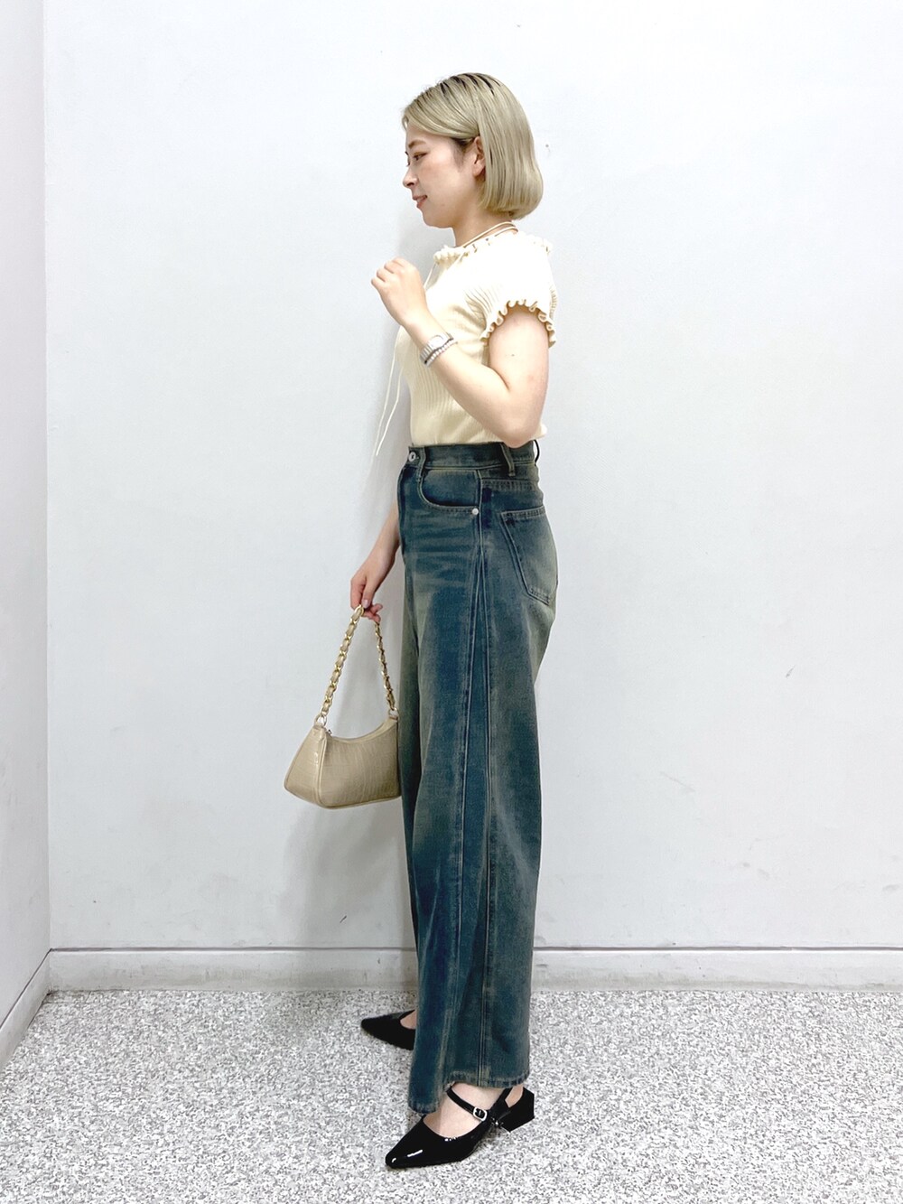 ブルー系のデニムパンツ、ブラック系のパンプス、ベージュ系のトートバッグを着用したレディースの夏コーディネートの2枚目の写真