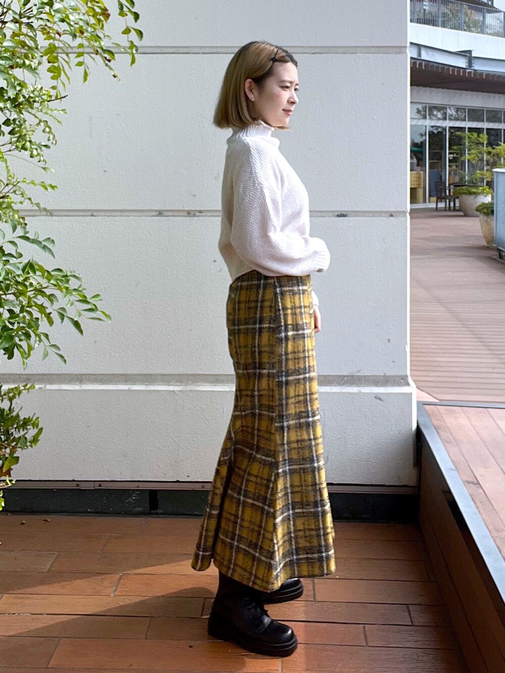 ホワイト系のニット/セーター、イエロー系のスカート、ブラック系のブーツを着用したレディースの秋コーディネートの4枚目の写真