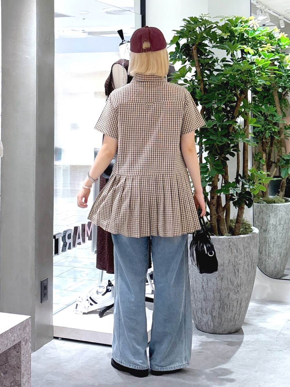 ベージュ系のワンピース、ブルー系のデニムパンツ、ブラック系のトートバッグを着用したレディースの夏コーディネートの3枚目の写真