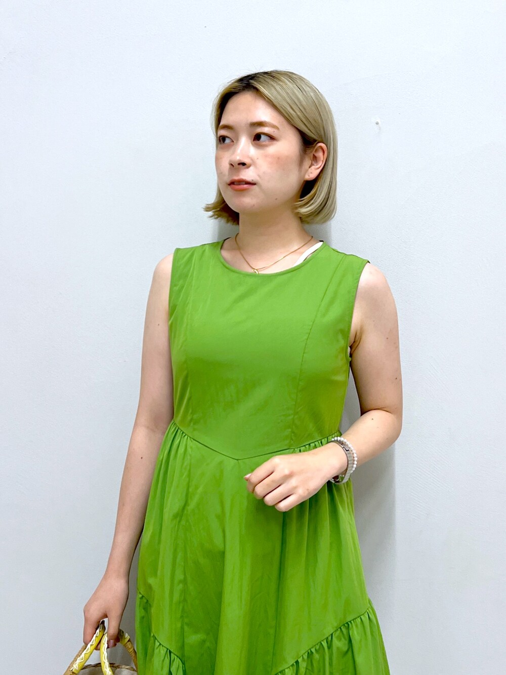 グリーン系のワンピース、イエロー系のかごバッグを着用したレディースの夏コーディネートの6枚目の写真