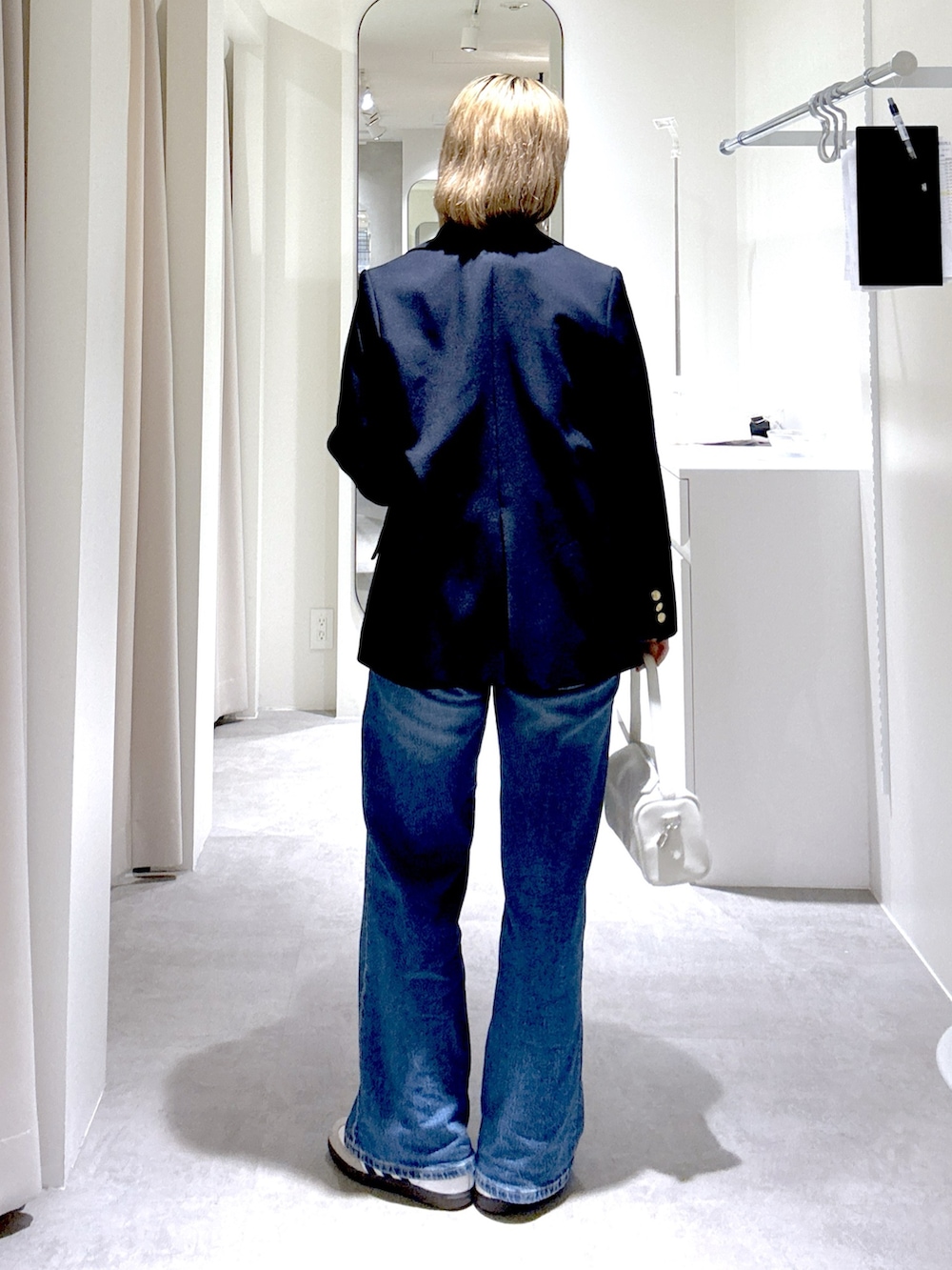 ホワイト系のハンドバッグ、ブルー系のテーラードジャケット、グレー系のニット/セーターを着用したレディースの春コーディネートの5枚目の写真