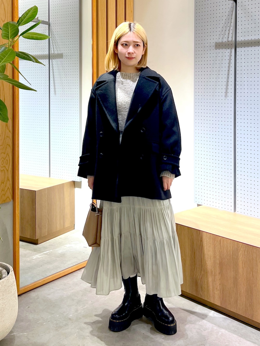 グレー系のニット/セーター、グリーン系のスカート、ベージュ系のショルダーバッグを着用したレディースの冬コーディネートの2枚目の写真