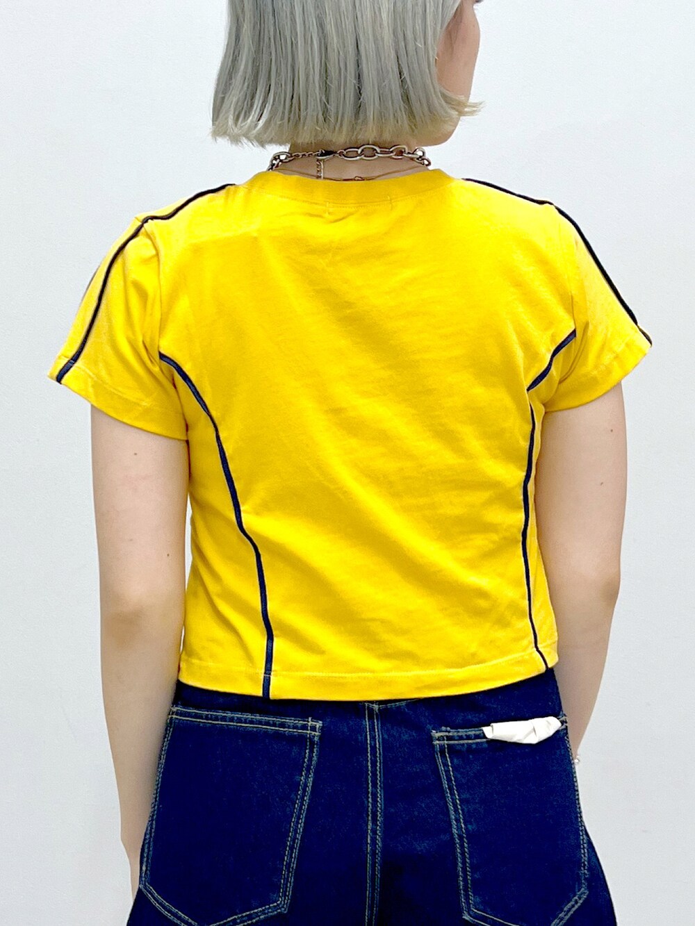 ブルー系のデニムパンツ、シルバー系のハンドバッグ、オレンジ系のTシャツ/カットソーを着用したレディースの秋コーディネートの5枚目の写真