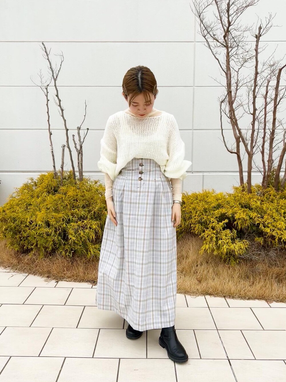 ホワイト系のニット/セーター、パープル系のスカート、ホワイト系のTシャツ/カットソーを着用したレディースの冬コーディネートの2枚目の写真