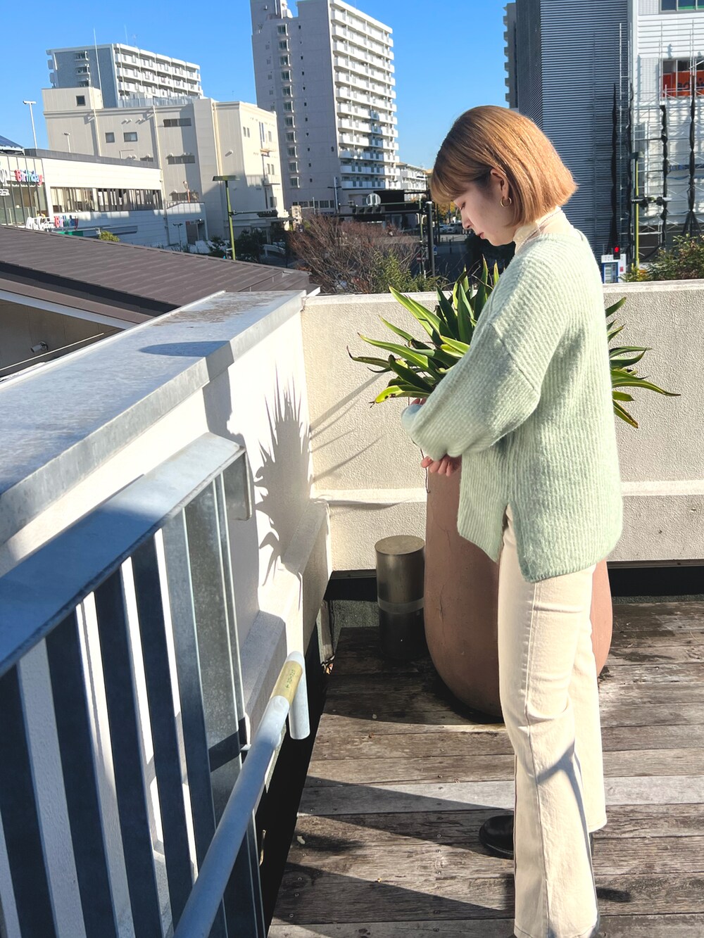 グリーン系のニット/セーター、ホワイト系のデニムパンツ、ホワイト系のストール/ショールを着用したレディースの冬コーディネートの2枚目の写真