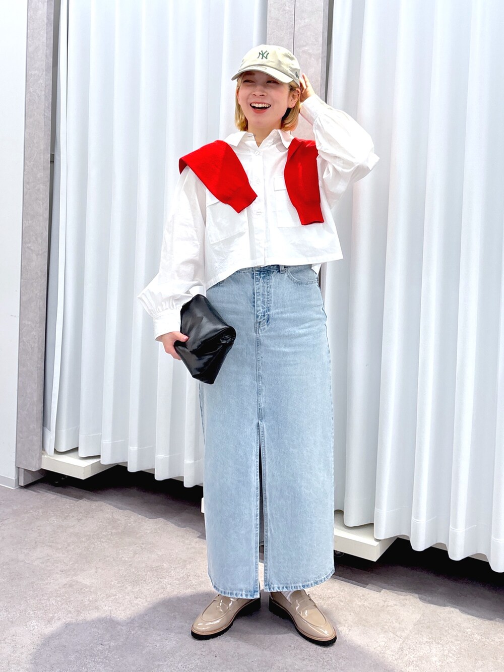 ブラック系のショルダーバッグ、ブルー系のデニムスカート、ホワイト系のシャツ/ブラウスを着用したレディースの春コーディネートの2枚目の写真