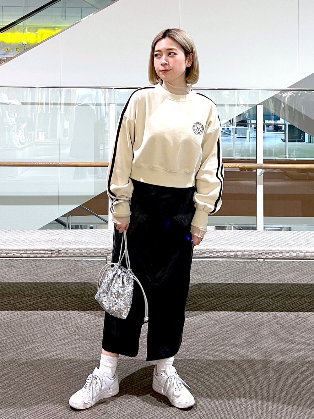 シルバー系のスカート、ピンク系のハンドバッグ、ホワイト系のスウェットを着用したレディースの冬コーディネートの2枚目の写真