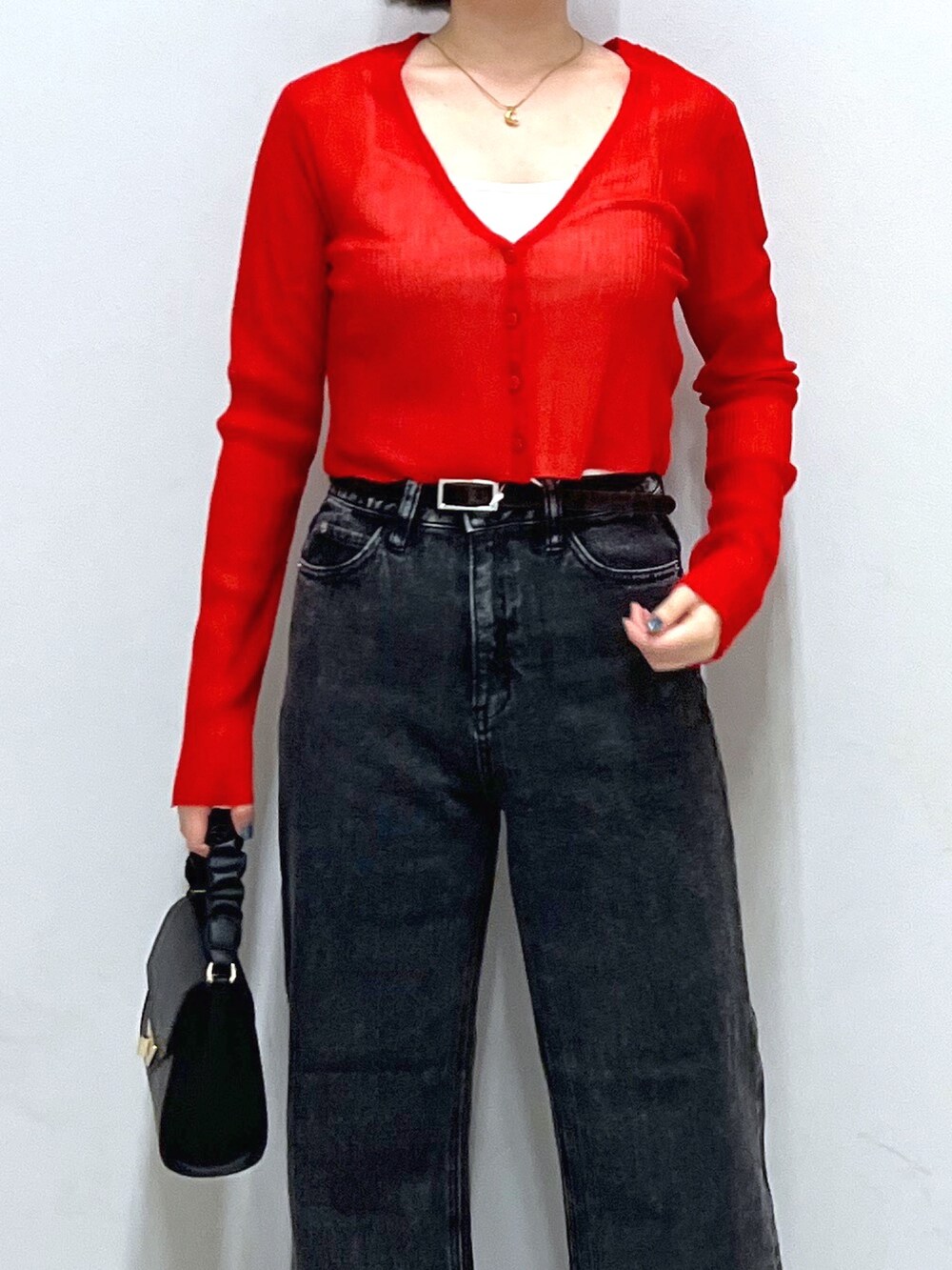 レッド系のカーディガン/ボレロ、ブラック系のデニムパンツ、ブラック系のショルダーバッグを着用したレディースの秋コーディネートの3枚目の写真