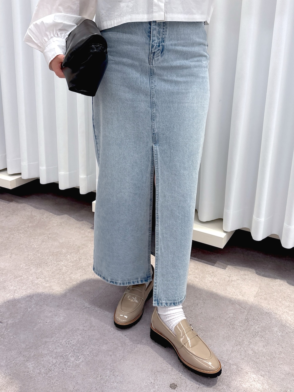 ブラック系のショルダーバッグ、ブルー系のデニムスカート、ホワイト系のシャツ/ブラウスを着用したレディースの春コーディネートの8枚目の写真