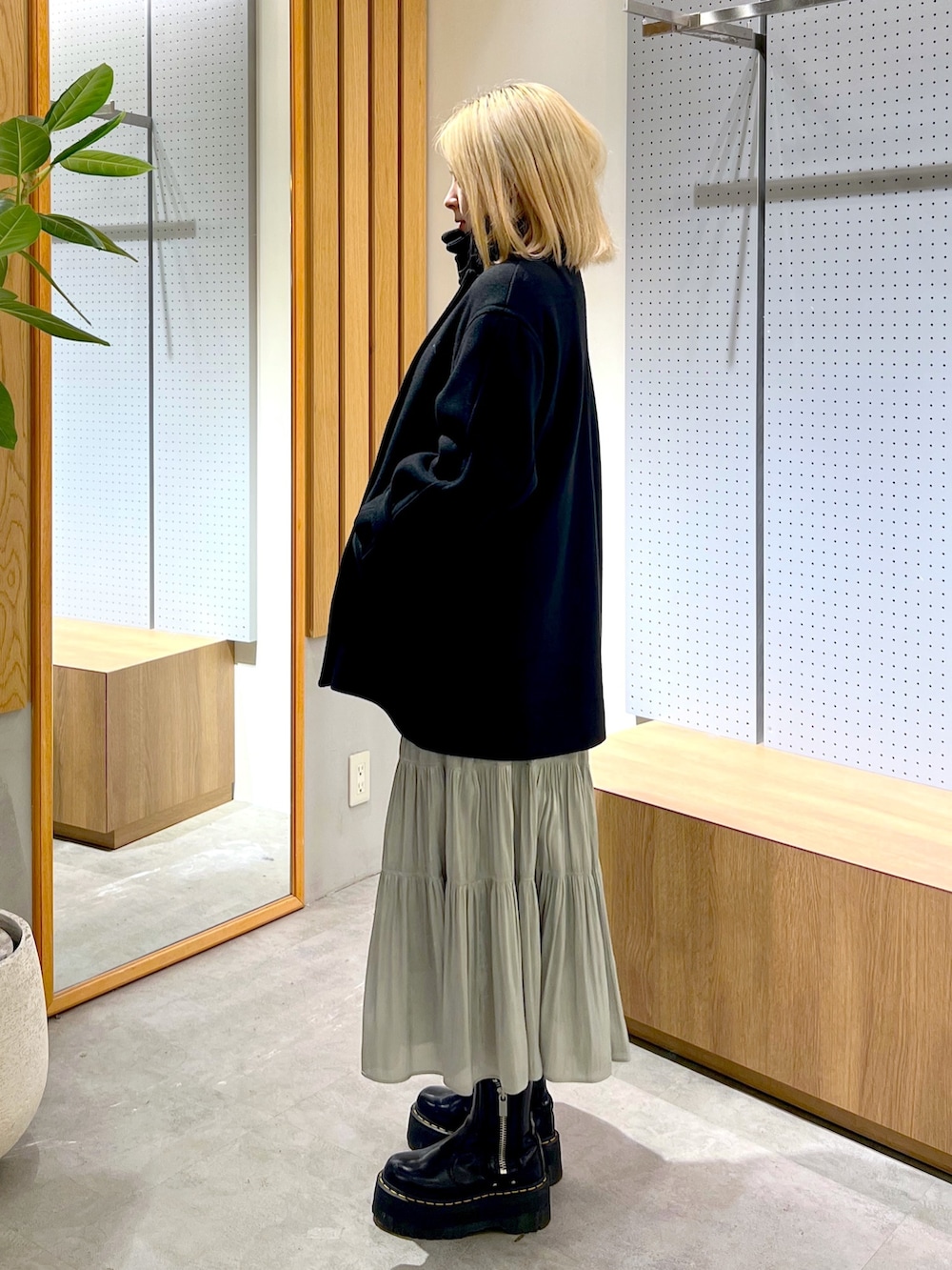 グレー系のニット/セーター、グリーン系のスカート、ベージュ系のショルダーバッグを着用したレディースの冬コーディネートの3枚目の写真