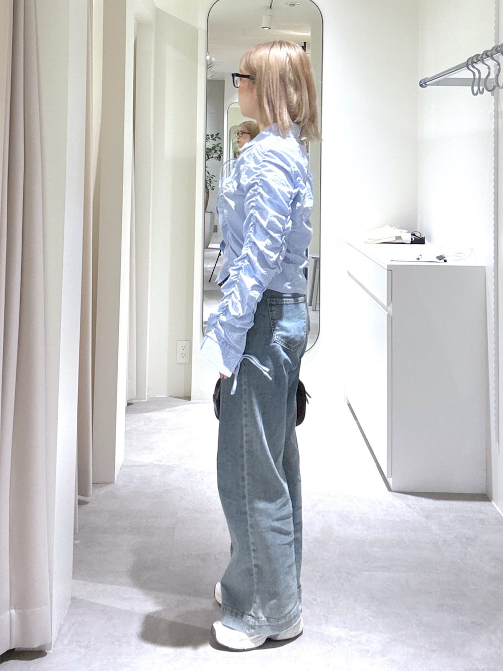 ブルー系のシャツ/ブラウス、ブルー系のデニムパンツ、ブラック系のハンドバッグを着用したレディースの春コーディネートの2枚目の写真