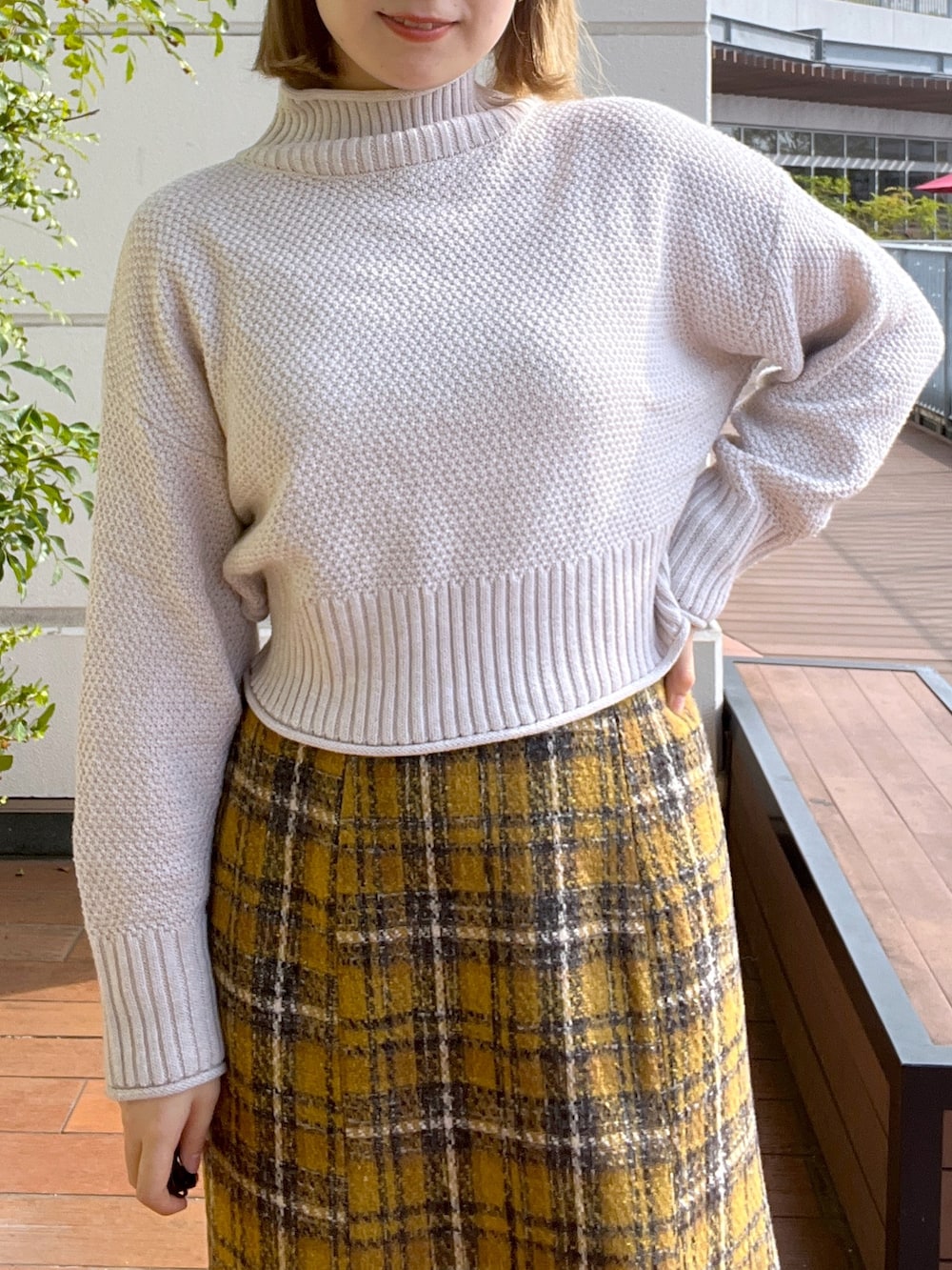 ホワイト系のニット/セーター、イエロー系のスカート、ブラック系のブーツを着用したレディースの秋コーディネートの5枚目の写真