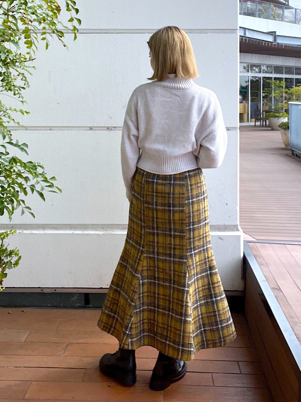 ホワイト系のニット/セーター、イエロー系のスカート、ブラック系のブーツを着用したレディースの秋コーディネートの3枚目の写真