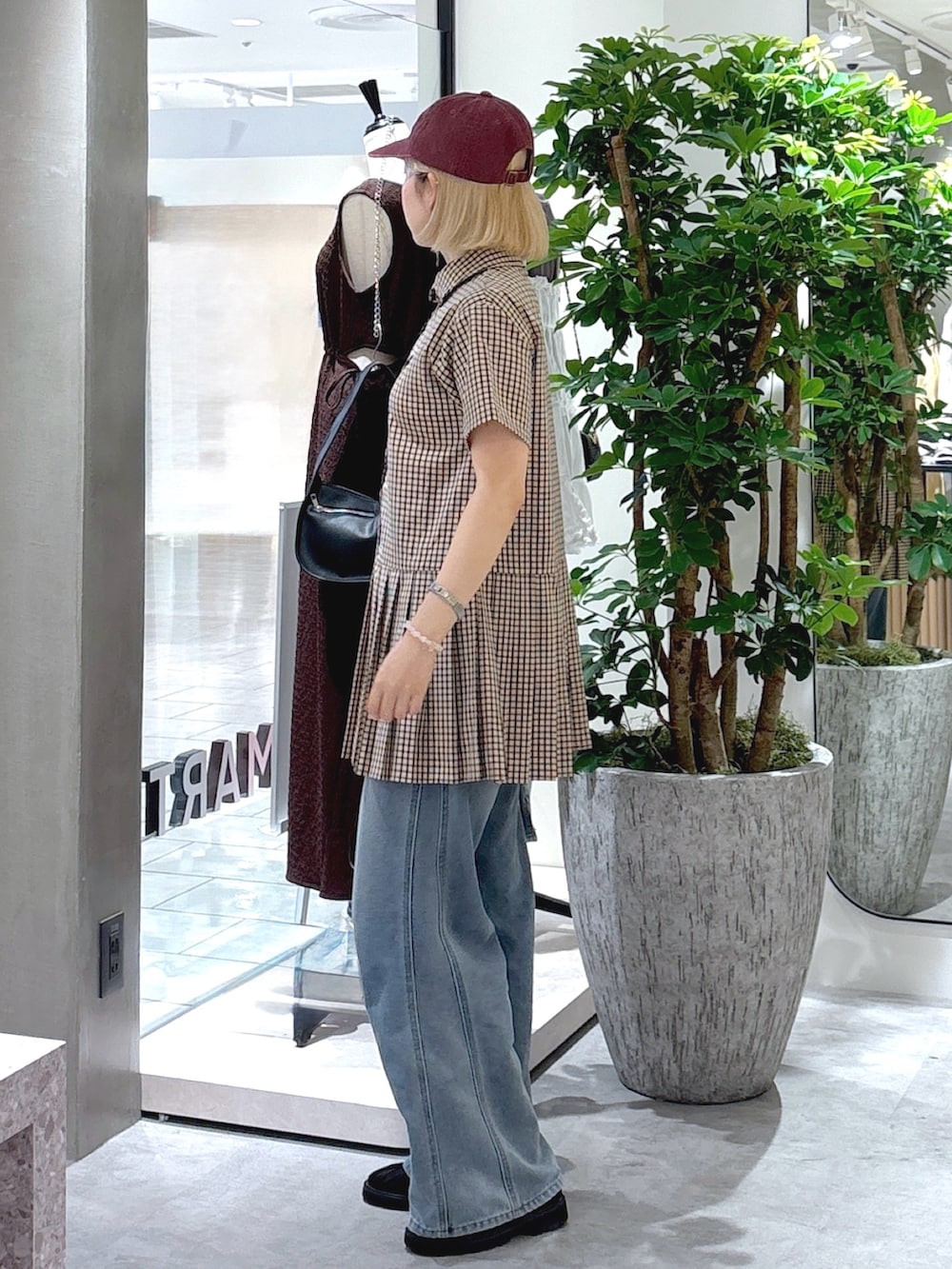 ベージュ系のワンピース、ブルー系のデニムパンツ、ブラック系のトートバッグを着用したレディースの夏コーディネートの2枚目の写真