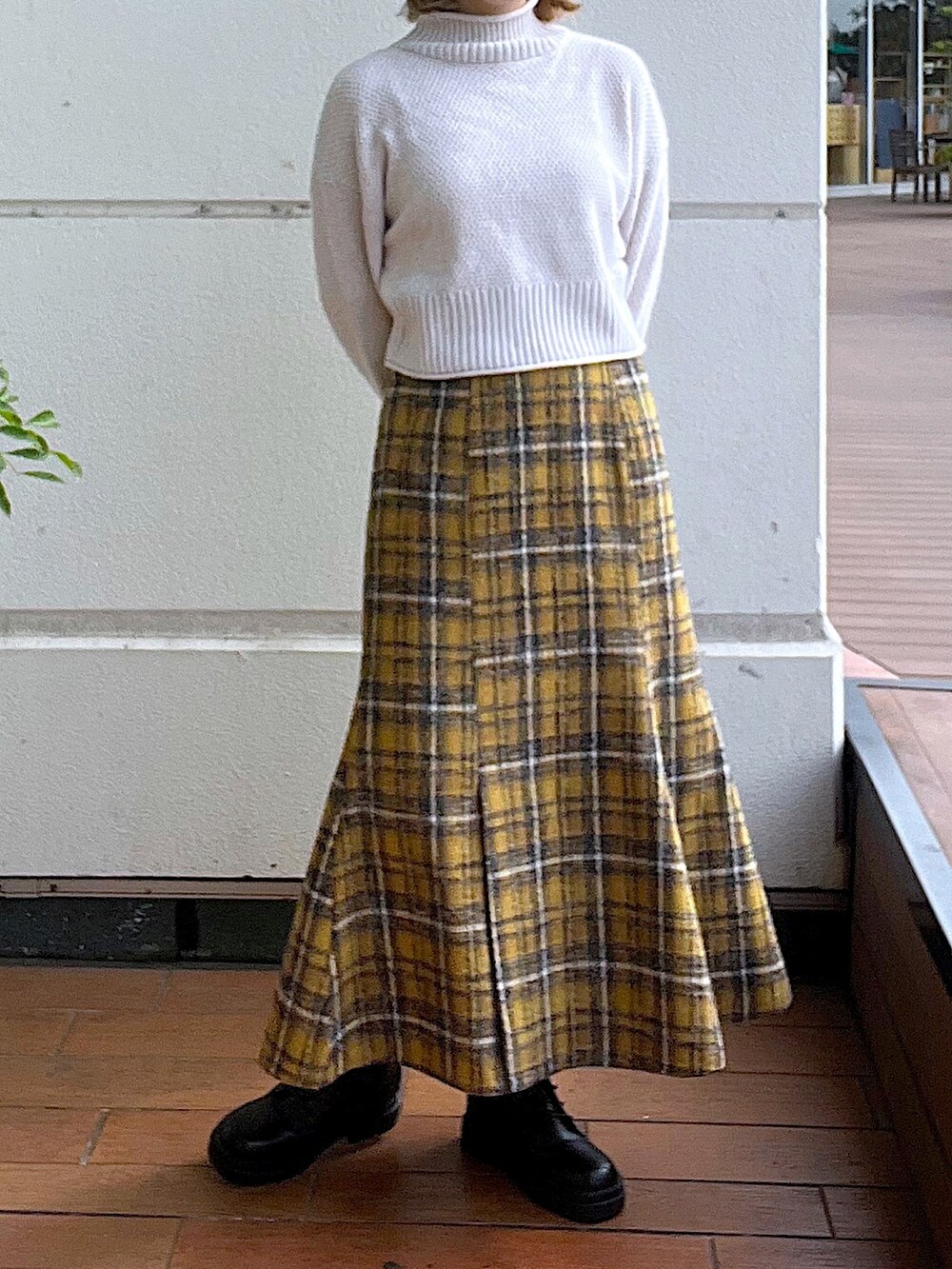 ホワイト系のニット/セーター、イエロー系のスカート、ブラック系のブーツを着用したレディースの秋コーディネートの2枚目の写真