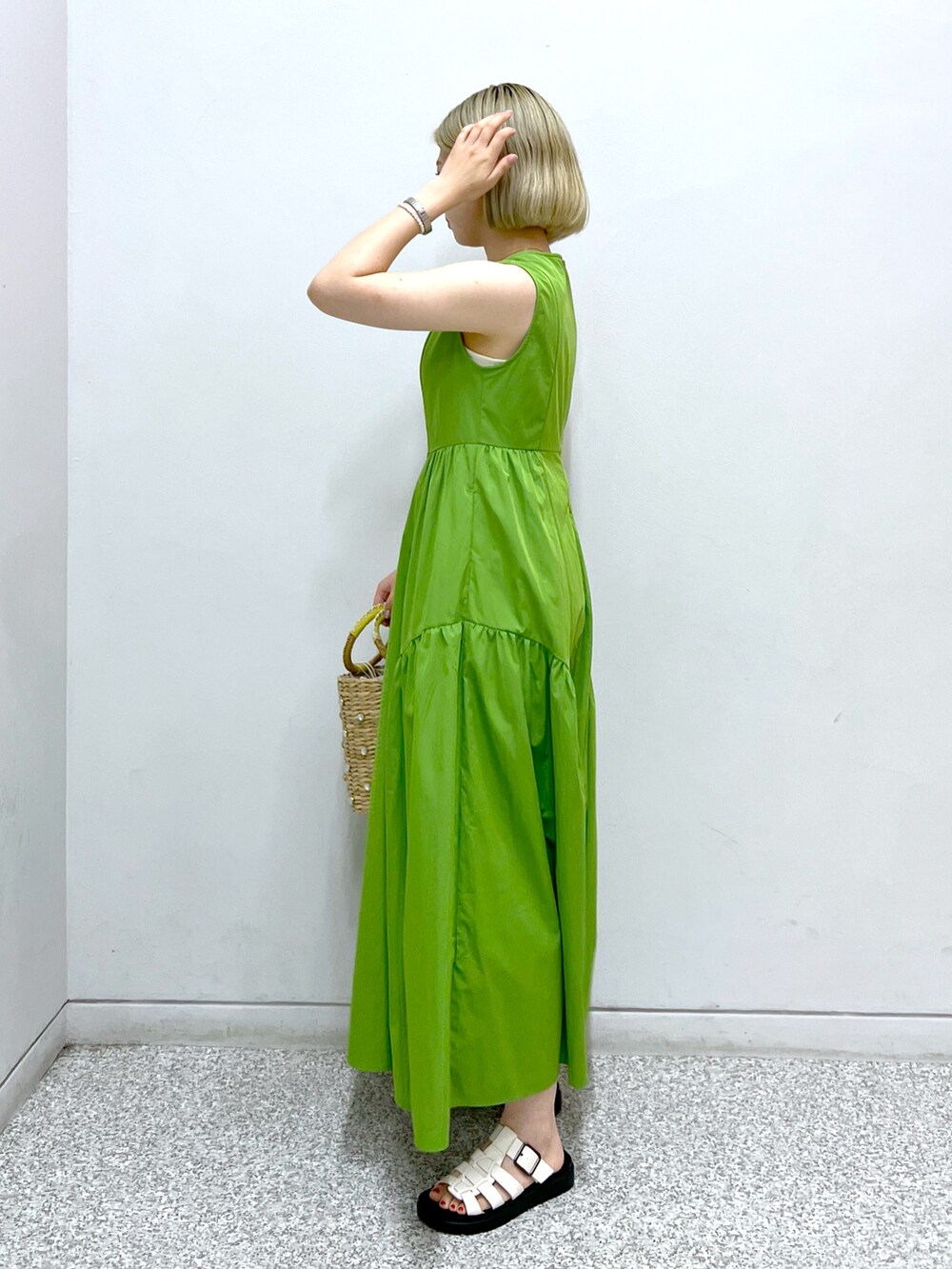 グリーン系のワンピース、イエロー系のかごバッグを着用したレディースの夏コーディネートの2枚目の写真