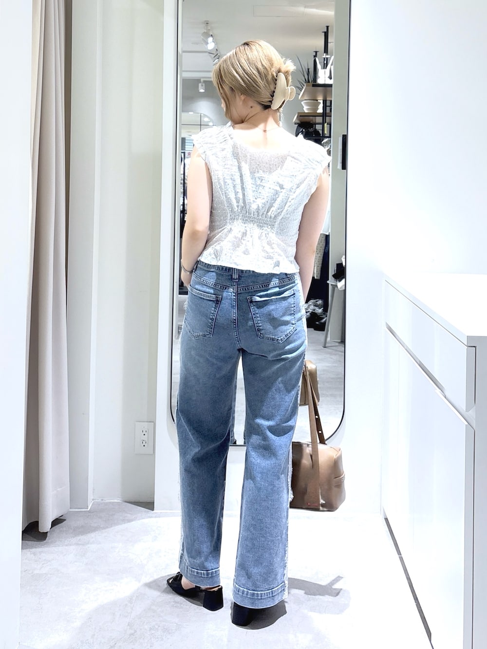 ホワイト系のシャツ/ブラウス、ブラウン系のショルダーバッグ、ブルー系のデニムパンツを着用したレディースの夏コーディネートの3枚目の写真