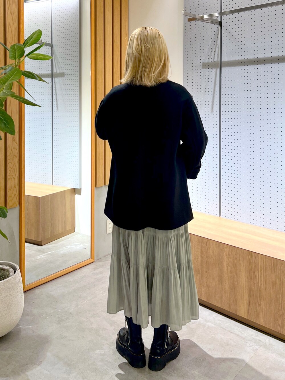 グレー系のニット/セーター、グリーン系のスカート、ベージュ系のショルダーバッグを着用したレディースの冬コーディネートの4枚目の写真