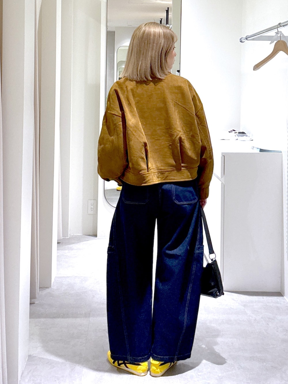 ブルー系のデニムパンツ、ブラック系のショルダーバッグ、ブラウン系のブルゾンを着用したレディースの冬コーディネートの3枚目の写真