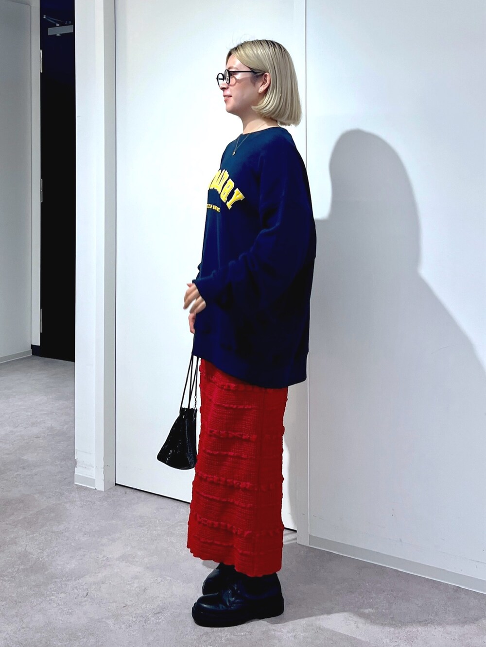 レッド系のスカート、ブルー系のスウェットを着用したレディースの秋コーディネートの2枚目の写真